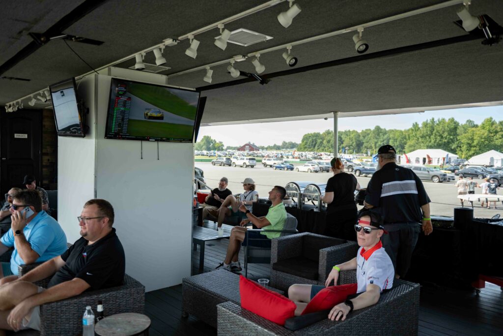 10 people sitting in a white hospitality trailer called the Oak Tree VIP Club watching the races at virginia international raceway