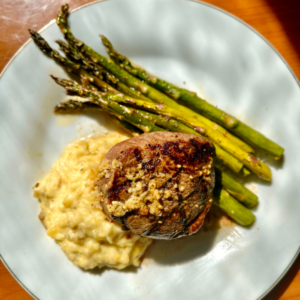 Steak, mashed potatoes, and asparagus on a white circle plate