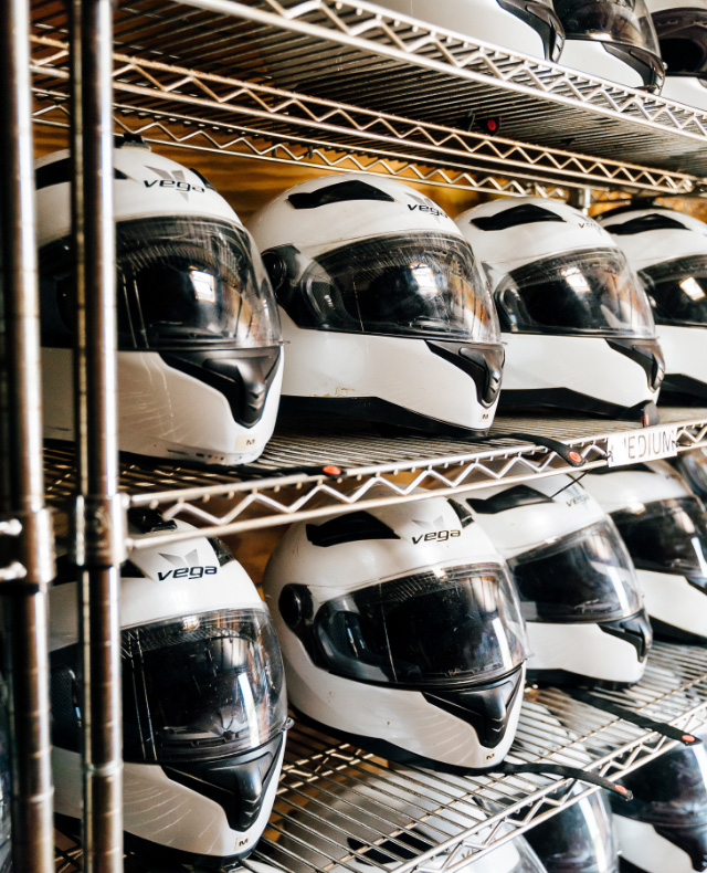 White and black go kart track helmets sitting on a metal organizing rack