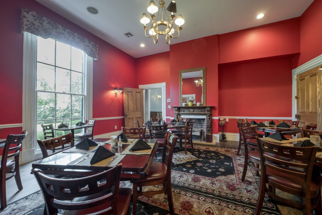 a room in the Oak Tree Tavern with red walls and tables and chairs