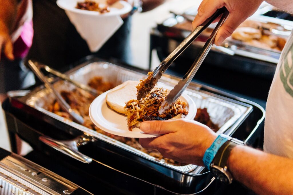 a person holding a plate of bbq pork