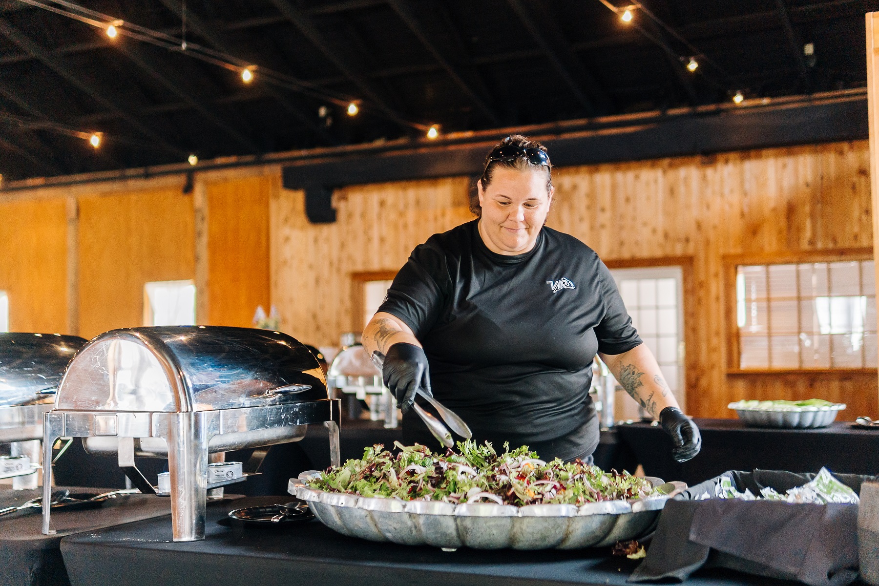 a woman in black gloves serving salad