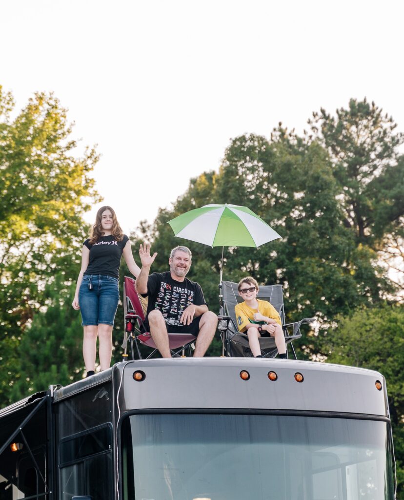 3 people on top of an RV waving