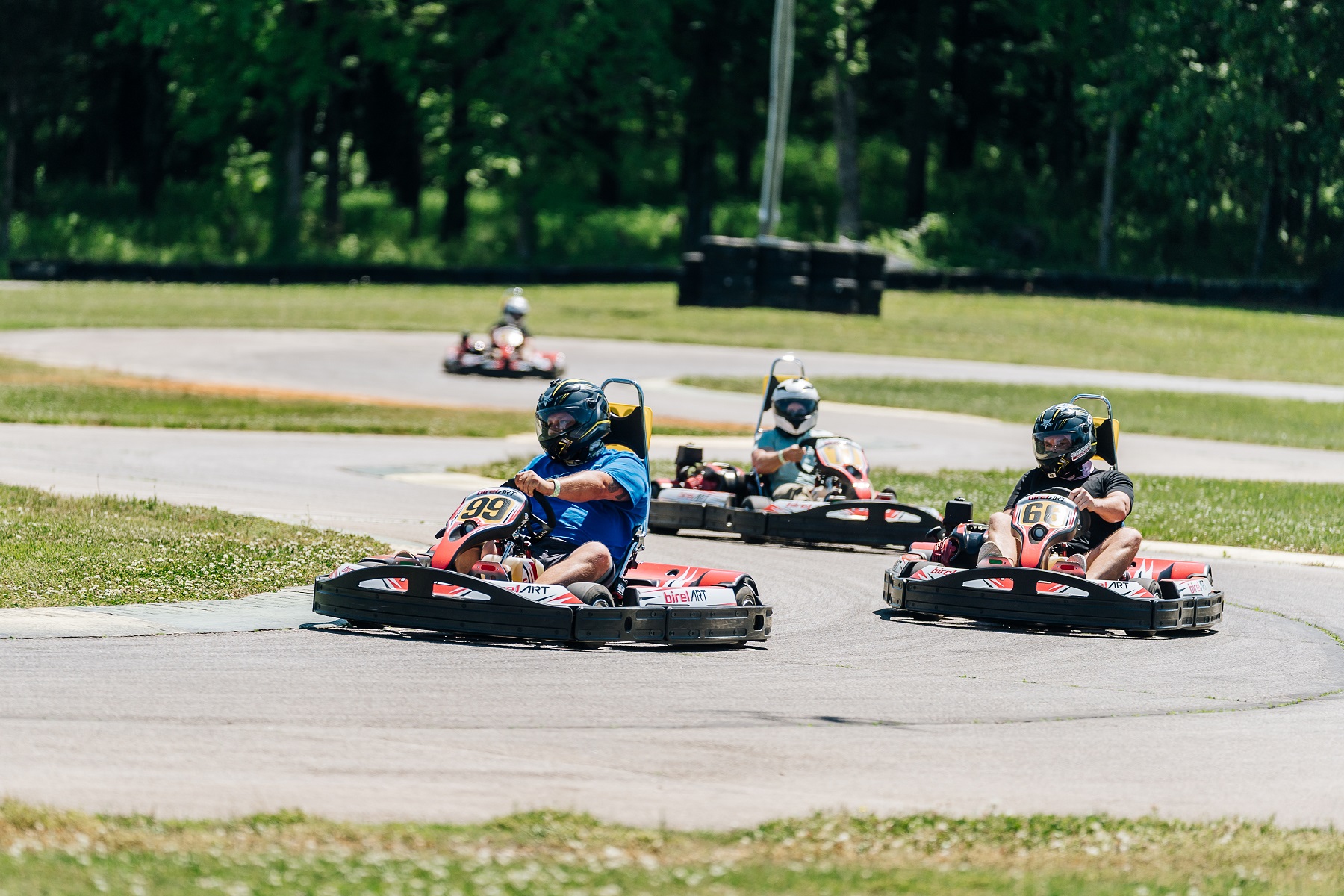 3 people in go karts on a sunny day