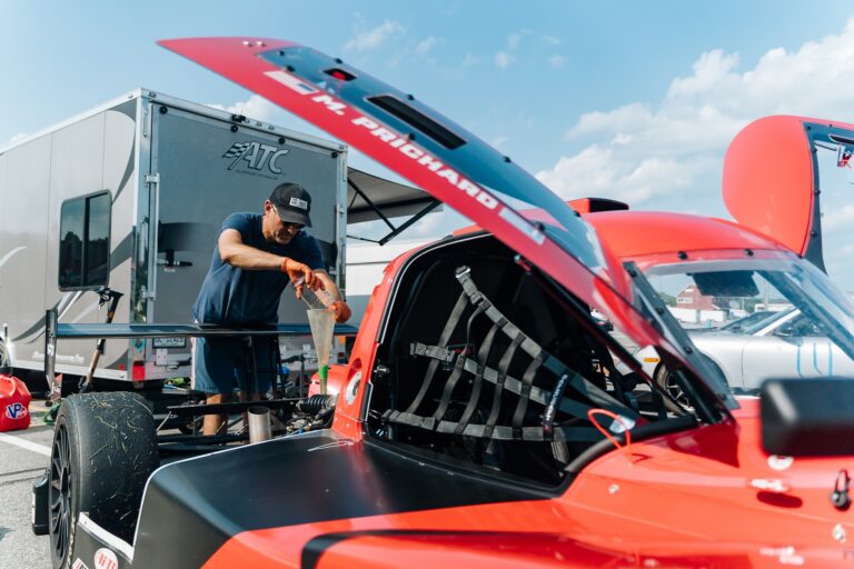 man servicing his car in the North Paddock during a VIR club day